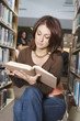 Female college student sitting, reading in library