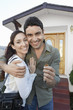 New homeowners standing in front of house holding key, portrait