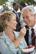 Cheerful elegant couple sharing dessert together at garden party