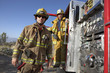 Two fire fighters standing by fire engine