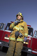 Fire fighter using two way radio in front of fire engine, low angle view
