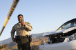 Foto: Police officer using walkie-talkie next to wrecked car Police officer using walkie-talkie next to wrecked car