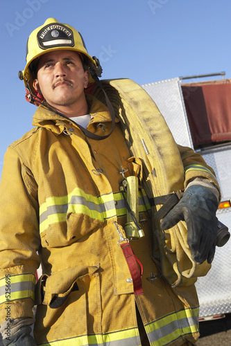Photo: Fire fighter standing with hose on shoulder Fire fighter standing with hose on shoulder