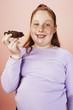 Overweight girl 13-15 smiling, holding brownie, portrait, front view