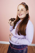 Overweight girl 13-15 smiling, holding brownie, hand on belly