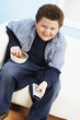 Overweight boy 13-15 Eating Junk Food, holding remote control