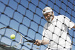 Senior man hitting tennis ball forehand near tennis net
