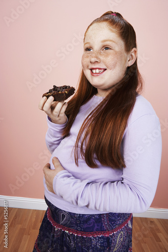 Photo: Overweight girl 13-15 smiling, holding brownie, hand on belly Overweight girl 13-15 smiling, holding brownie, hand on belly