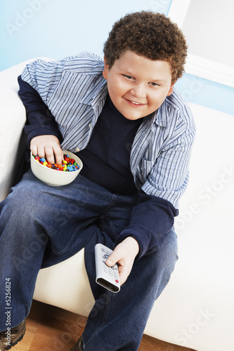 Photo: Overweight boy 13-15 Eating Junk Food, holding remote control Overweight boy 13-15 Eating Junk Food, holding remote control
