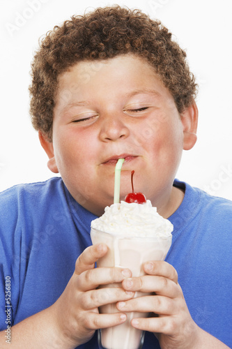 Foto: Overweight boy 13-15 drinking milk shake, eyes closed, front view Overweight boy 13-15 drinking milk shake, eyes closed, front view