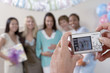 Woman taking photo of friends at baby shower, focus on camera