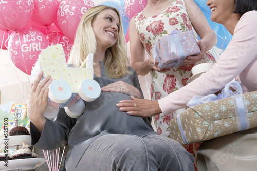 Foto: Friends giving gifts to woman at baby shower Friends giving gifts to woman at baby shower