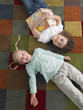 Two girls lying down on library floor, view from above