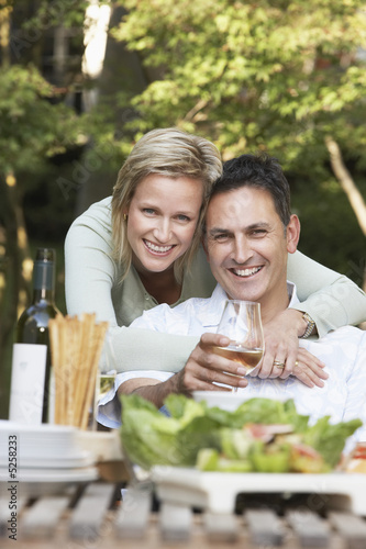 Photo: Couple embracing at outdoor table, portrait Couple embracing at outdoor table, portrait