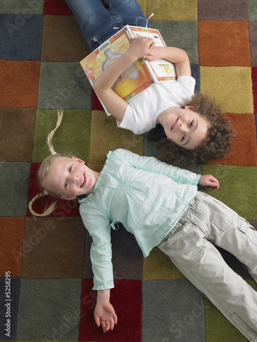 Photo: Two girls lying down on library floor, view from above Two girls lying down on library floor, view from above
