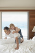 Son riding piggy back on father on bed