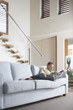 Mid-adult Man reclining on sofa, Reading Newspaper