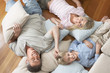 Father and Children Lying on pillows and cushions on wood Floor, overhead view