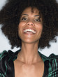 Woman with afro smiling head and shoulders in studio