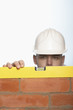 Man in hard hat using level to check brick wall, high section