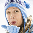 smiling blond woman blowing kiss at viewer.