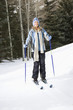 Female skier wearing blue ski clothing standing on ski slope.