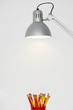 Angle poise lamp shining on cup of pencils