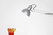 Angle poise lamp shining on cup of pencils