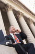 Businessman using mobile phone outside courthouse