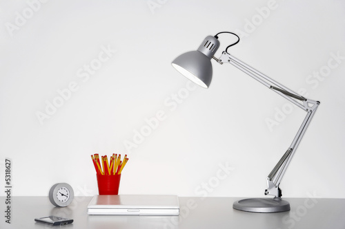 Foto: Angle poise lamp, laptop, clock, pencils and PDA on desk Angle poise lamp, laptop, clock, pencils and PDA on desk