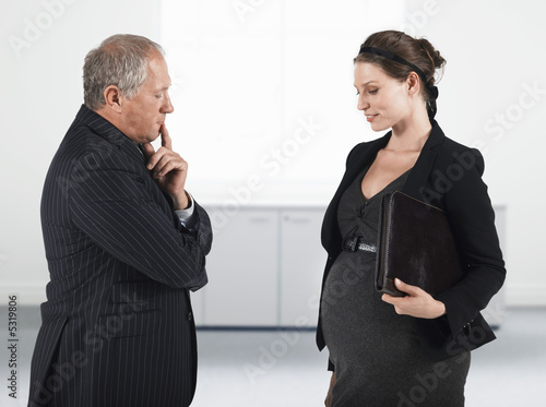 Photo: Boss talking to pregnant businesswoman, half length Boss talking to pregnant businesswoman, half length