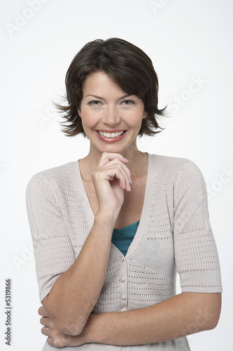Photo: Smiling Woman standing, hand on chin Smiling Woman standing, hand on chin