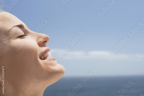 Young woman with eyes closed on beach, close-up
