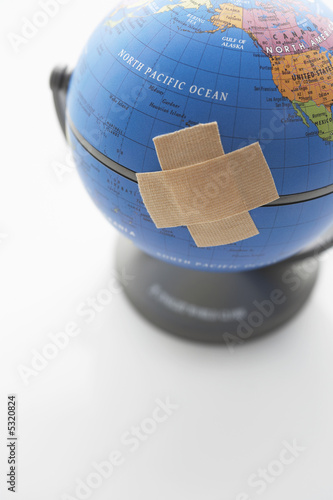 Photo: Two pieces of sticking plaster on globe, close-up Two pieces of sticking plaster on globe, close-up