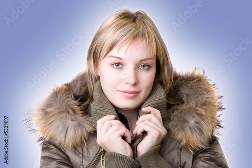 Foto: young girl in a jacket with a fur collar on a light blue backgro young girl in a jacket with a fur collar on a light blue backgro