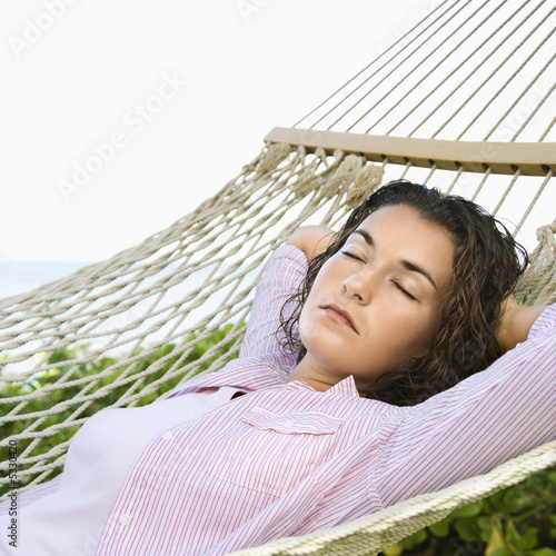 Foto: Female lying in hammock with arms behind head sleeping. Female lying in hammock with arms behind head sleeping.