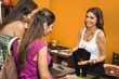 Sales clerk showing necklace to women shoppers in boutique.