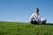 Businessman meditating on green grass