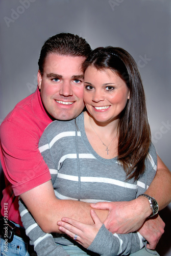 Photo: A young married couple smiling in an embrace. A young married couple smiling in an embrace.