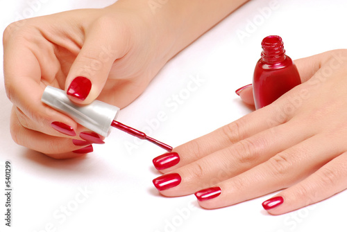 Photo: Woman brushing her nails in the red color Woman brushing her nails in the red color