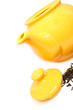 Yellow teapot with tea leaves isolated on white