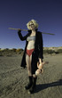 Blonde science fiction model weilding a stick and holding a doll