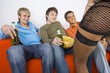 Three young men sitting on orange couch