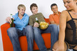 Three young men sitting on orange couch
