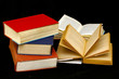 stack of three old books, two with pages open as if being read stack of three old books, two with pages open as if being read