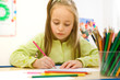 Pretty girl sitting and drawing with colored pencils