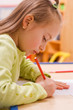 Pretty girl sitting and drawing with red pencil
