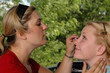 A makeup artist applies cosmetics to a female model