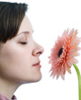 Girl on white background smelling pink flower