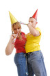 Young couple wearing carnival hats playing with pipes